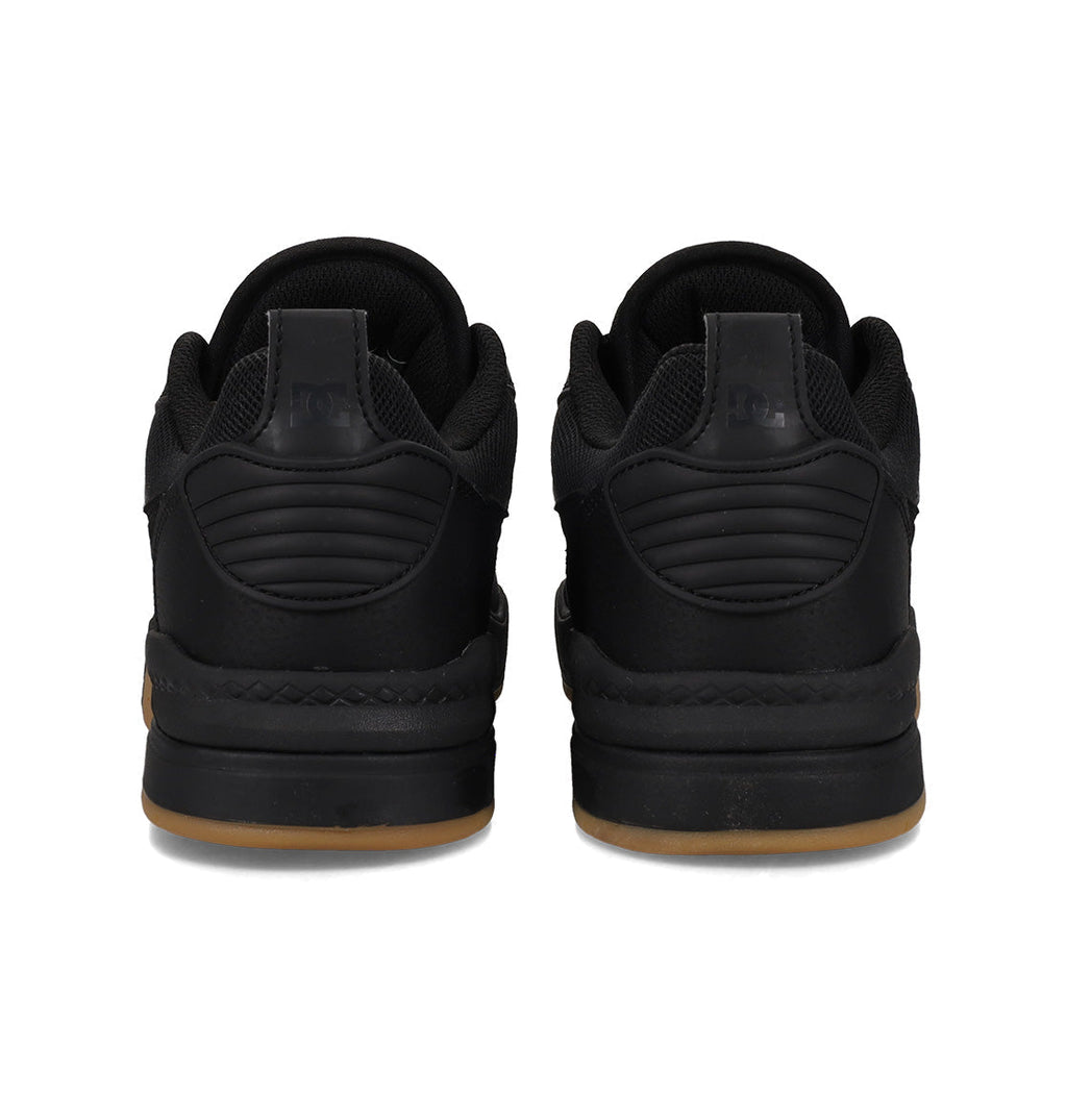 A pair of black DC Shoes Men’s Ascend Skate Shoes viewed from the back, featuring thick soles with a light brown gum base, quilted heel detailing, and black laces—these sneakers seamlessly blend modern comfort with timeless style.