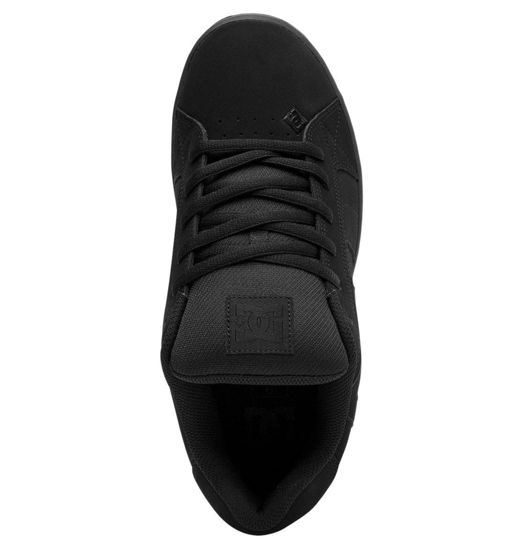Top view of the DC Shoes Men’s Net Shoes in black, featuring black laces, a textured tongue with a stitched DC logo patch, and subtle branding near the toe. Constructed from durable materials, these puffy sneakers deliver both comfort and lasting wear.