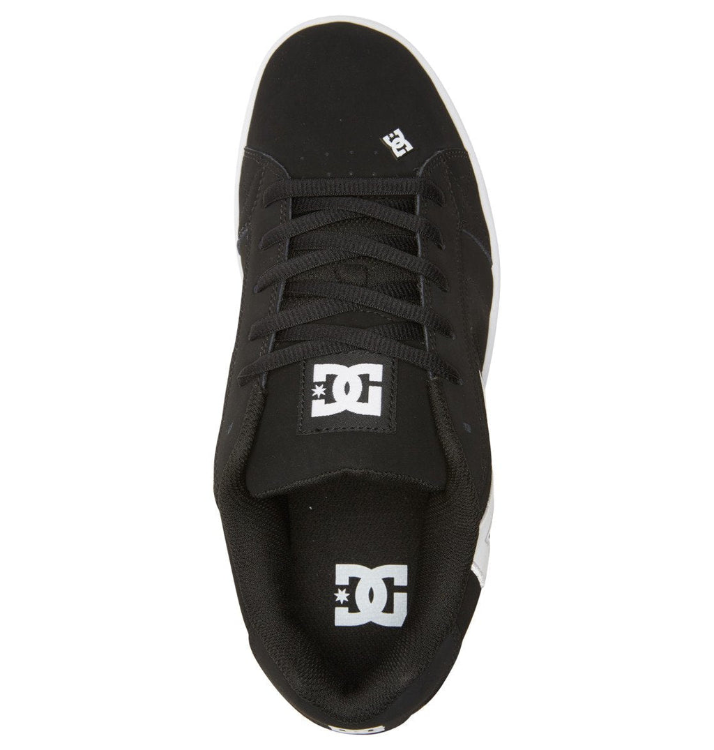 A top-down view of the Men’s Net Shoes by DC Shoes shows a black puffy sneaker crafted from durable materials, with bold white DC Shoes logos on the tongue and toe, black laces, and a contrasting white sole.