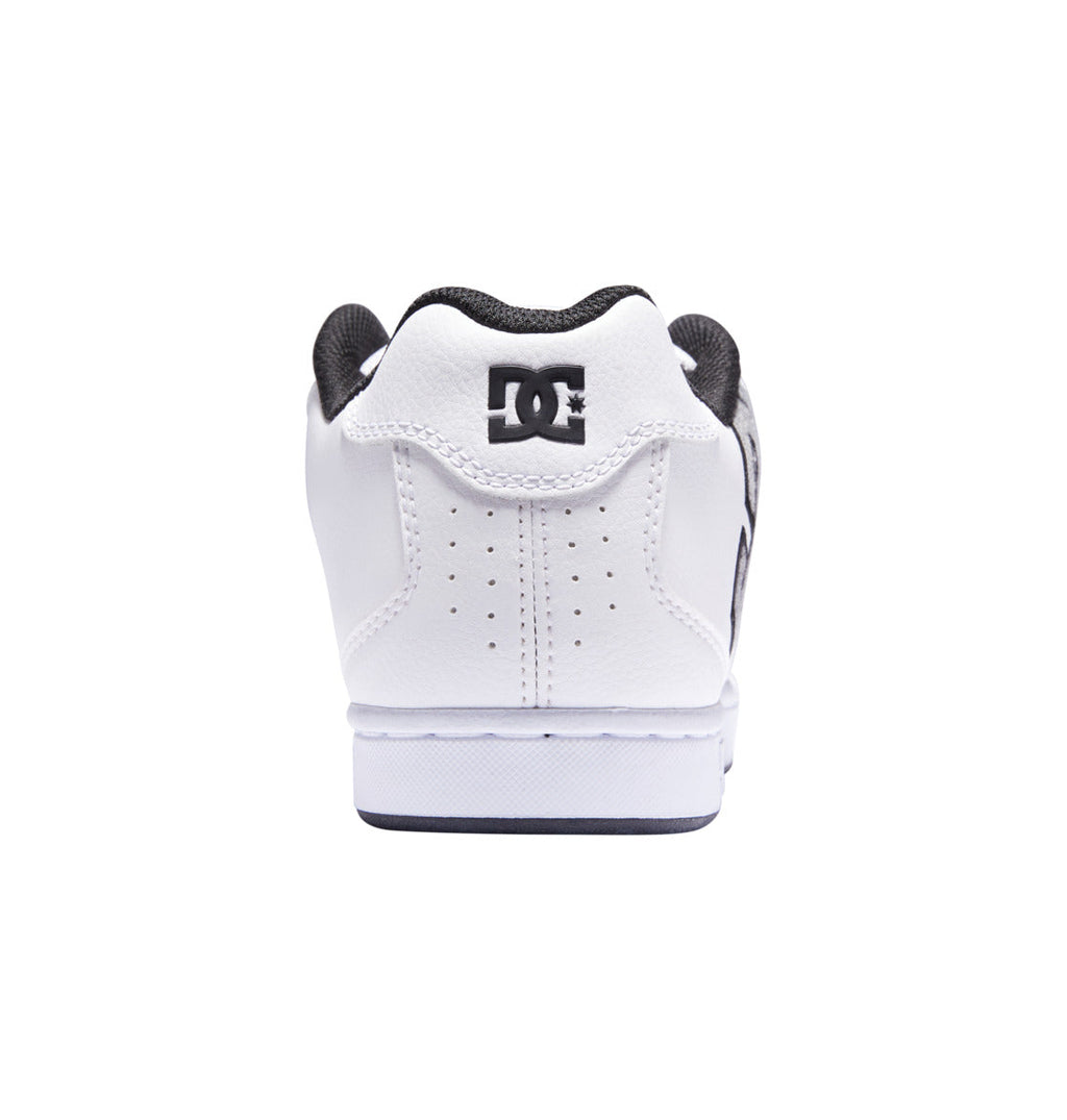 A men’s Net shoe by DC Shoes in white, viewed from the back and centered on a white background. It features bold branding with a black DC Shoes logo on the heel and has a black inner lining.