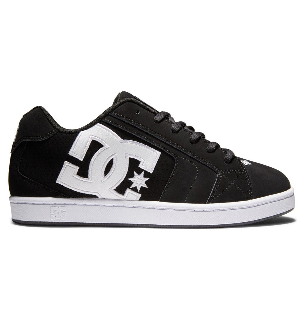 A side view of the Men’s Net Shoes by DC Shoes, featuring a black design crafted from durable materials, with a prominent white DC logo and star on the side, bold branding details, black laces, and a white sole, set against a white background.