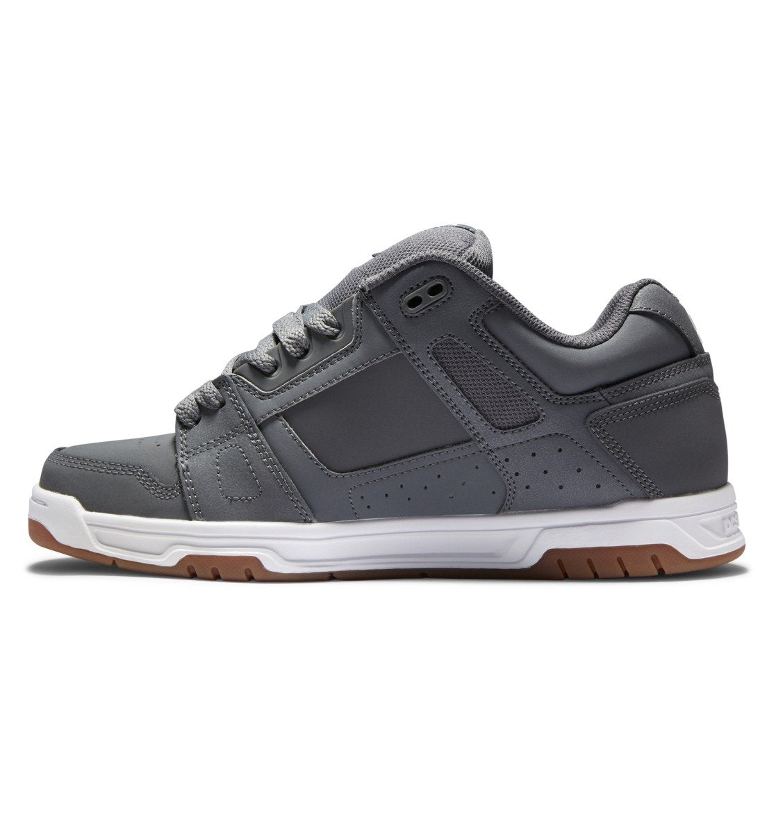 A side view of the DC Shoes Men’s Stag Shoe in gray, featuring a durable white and brown rubber cupsole, an oversized puff padded collar, and gray laces, displayed against a white background.