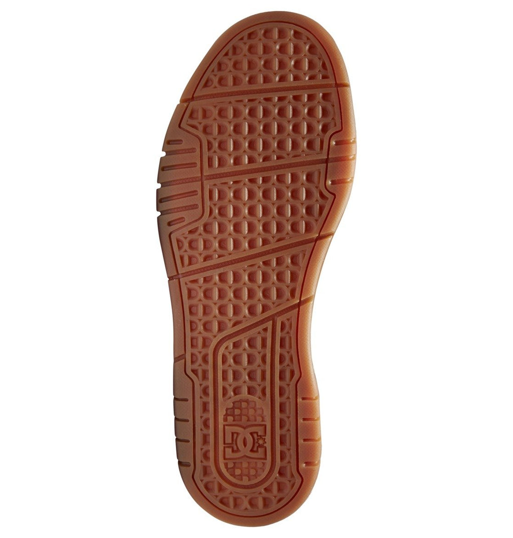 The image displays the brown rubber sole of the DC Shoes Men’s Stag Shoes, showcasing geometric tread patterns, a durable cupsole design, and the embossed DC Shoes logo near the heel.