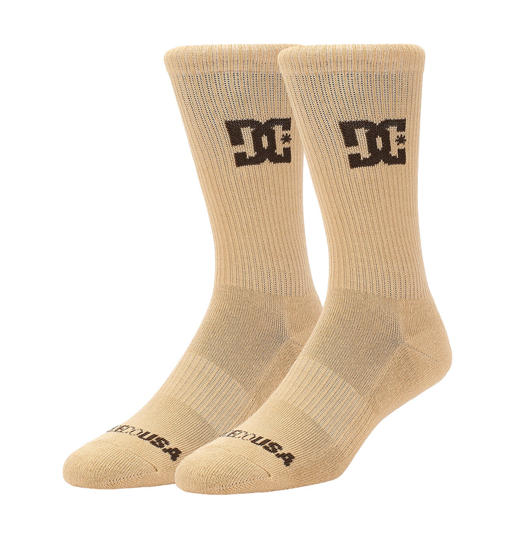 A 6-pack of beige crew socks by DC Shoes, each featuring a black logo on the side and “DC USA” text on the toe, displayed upright against a white background.