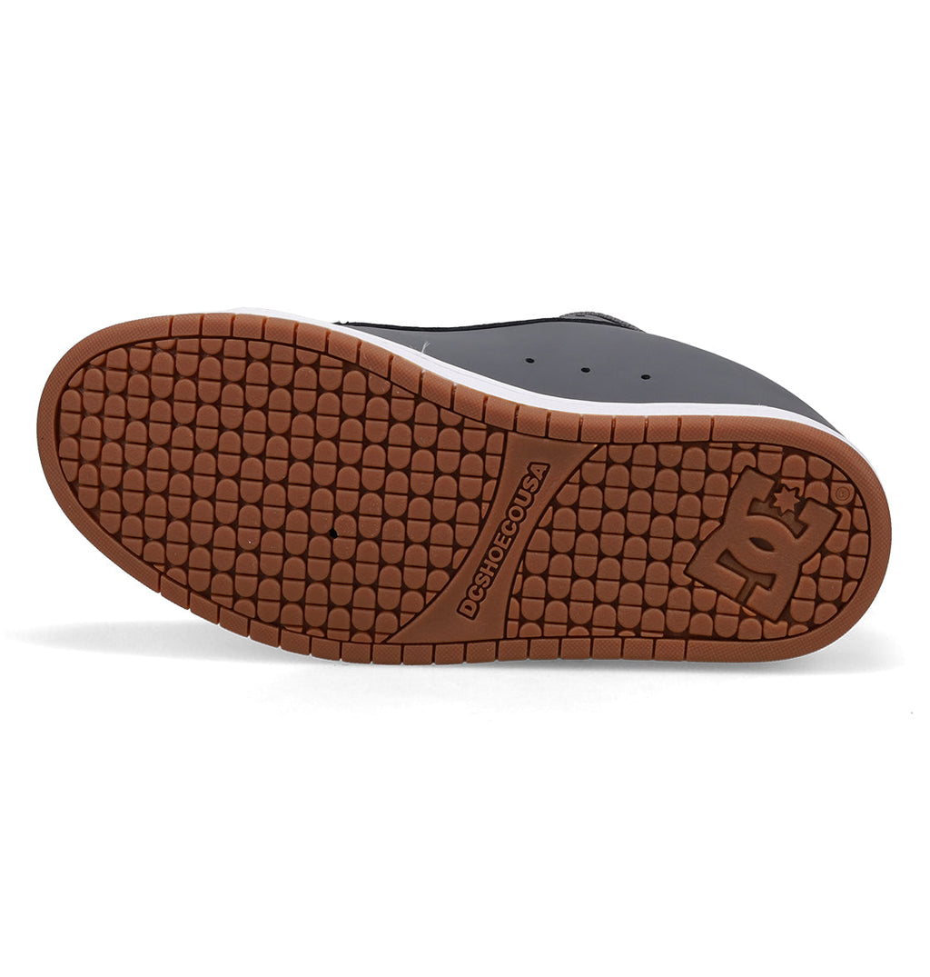 The image displays the sole of the Men’s Court Graffik Shoes by DC Shoes, showcasing a brown textured rubber tread with the DC Shoes logo embossed near the heel. This classic model exemplifies DC’s iconic chunky skate shoe design.