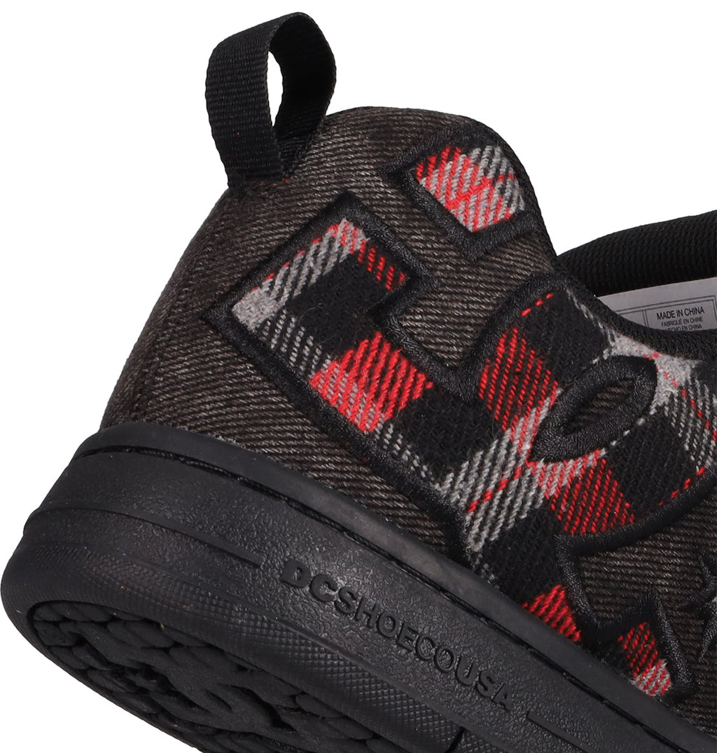 Close-up of DC Shoes Men's Court Graffik SE Shoes, a black sneaker with red and gray plaid, premium upper, large embroidered letters, black heel pull tab, and black textured sole embossed with DCSHOECOUSA.