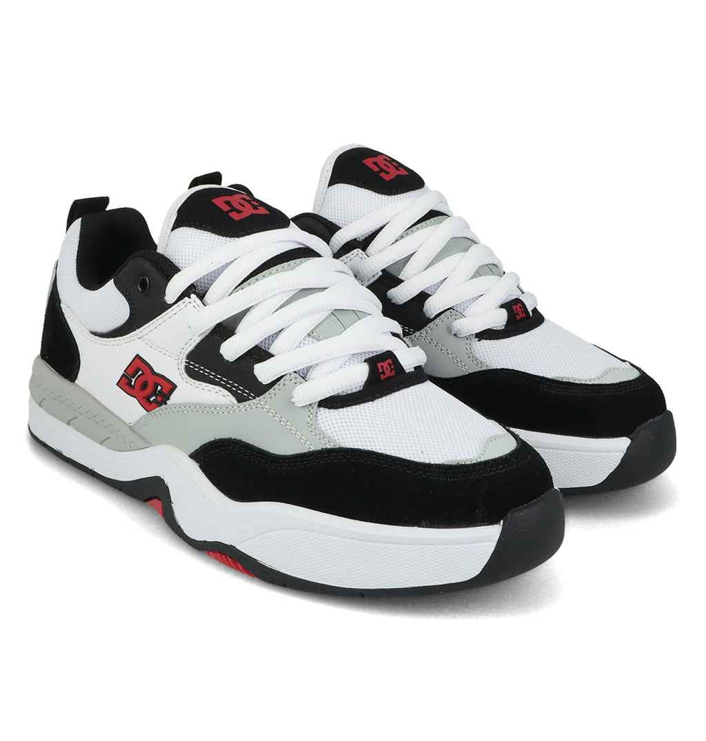 A pair of DC Shoes Men’s Ascend Skate Shoes in black, white, and gray featuring Josh Kalis-inspired design elements, red logo detailing, crisp white laces, and thick white rubber soles that embody modern comfort and the signature DNA of DC Shoes.
