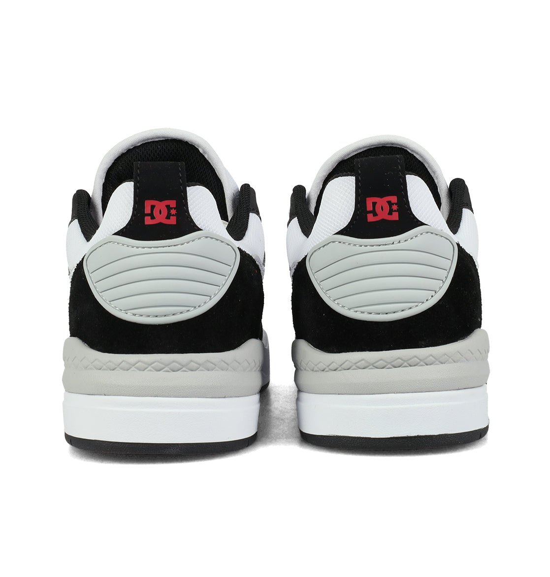 A pair of DC Shoes Men’s Ascend Skate Shoes in black, white, and gray are shown from the back, featuring red DC logos on the heel tabs—these sneakers perfectly embody authentic DC style while offering modern comfort.