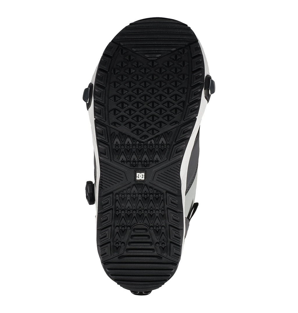 The bottom view of a black and white Men’s Judge Step On® Snowboard Boot from DC Shoes reveals a detailed tread pattern, metal cleats, and a small DC logo centered on the sole, showcasing features influenced by premium snowboard boot design and advanced BOA® Fit System technology.