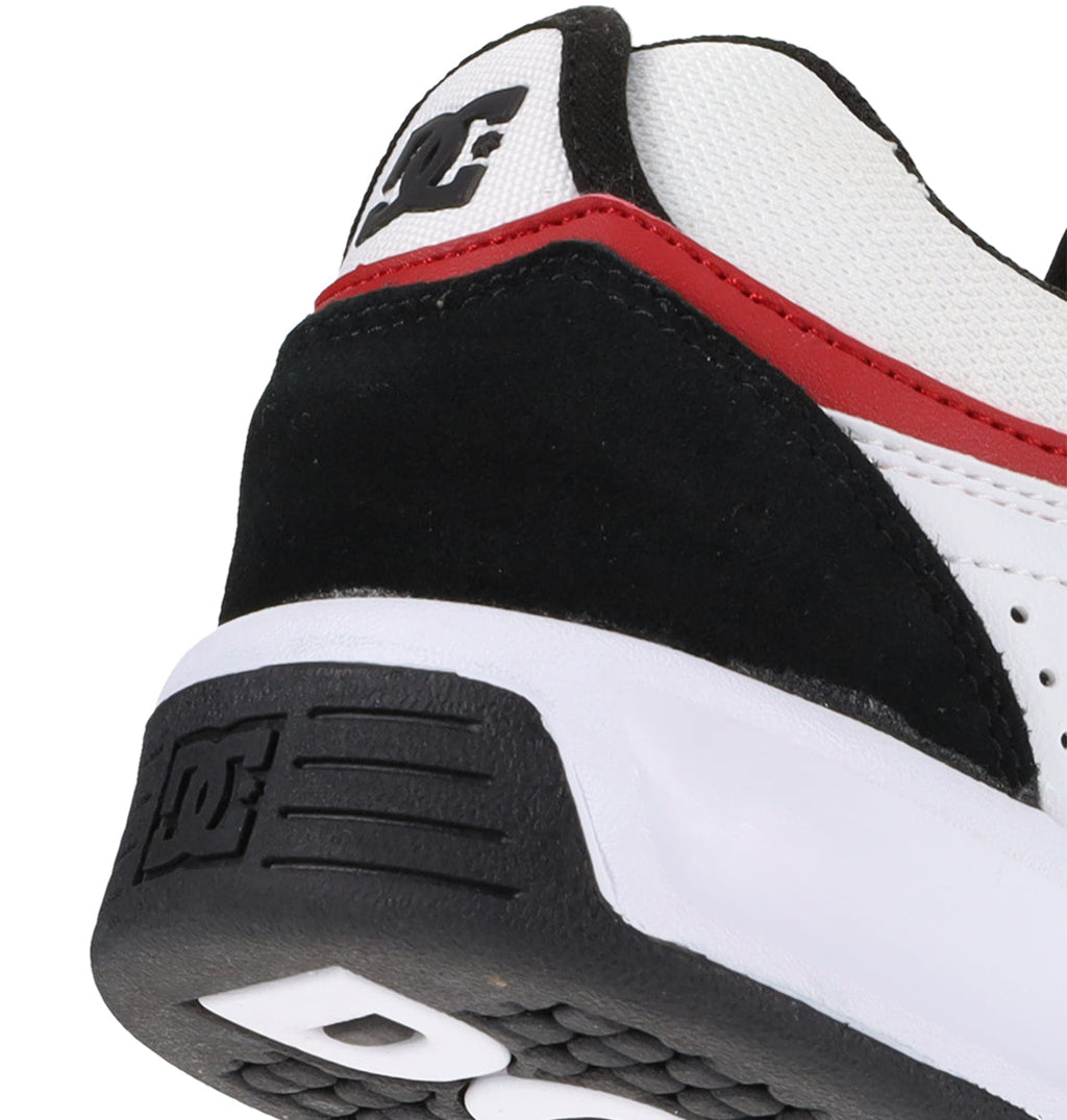 Close-up of the heel of the DC Shoes Men’s Kalynx Zero Shoes in black, white, and red. Featuring the iconic DC Shoes logo on the heel tab and outsole, this skate shoe boasts a white upper with black suede overlays and a bold red accent strip—delivering classic DC Shoes style that’s perfect for your next skate session.