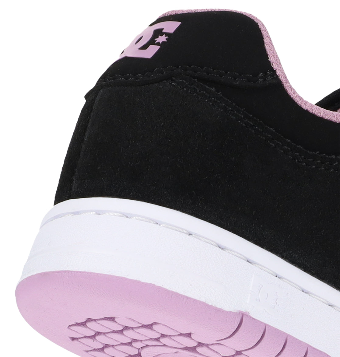 Close-up of the back and sole of a black Women’s Manteca 4 Shoe by DC Shoes, featuring a white midsole and light pink outsole. This classic design showcases the iconic DC logo in pink on the black heel tab with coordinating pink trim along the upper edge.