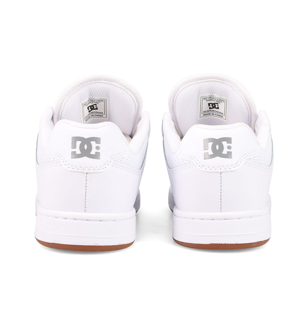 A pair of white DC Shoes Women's Manteca 4 is shown from the back, featuring a gray DC logo on the heel, white soles, and brown edges—highlighting the performance-driven design.