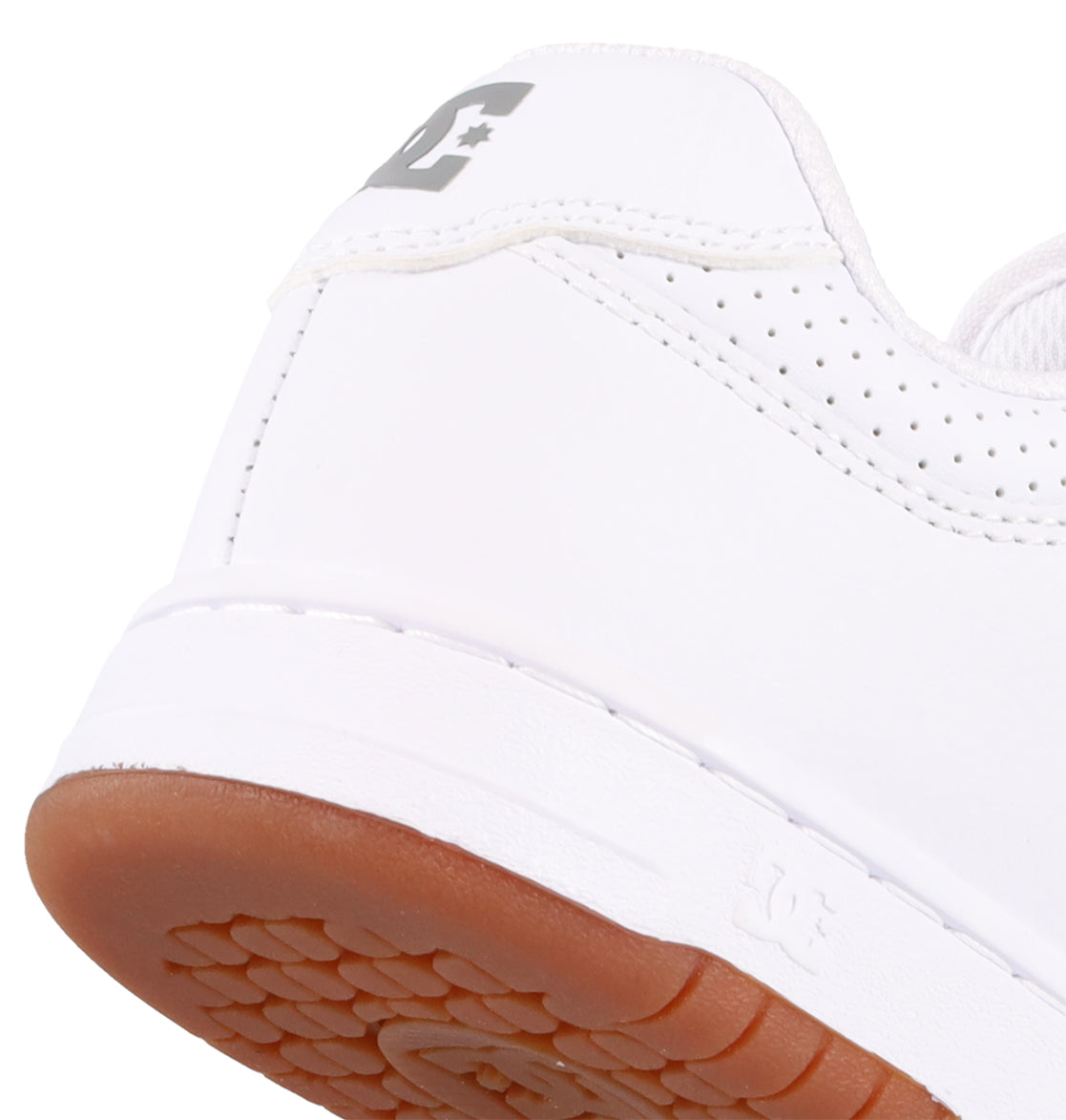 Close-up of the heel of a Women’s Manteca 4 Shoe from DC Shoes, showcasing a brown rubber sole, perforated accents, and a gray DC logo on the back—combining classic style with performance-driven design.