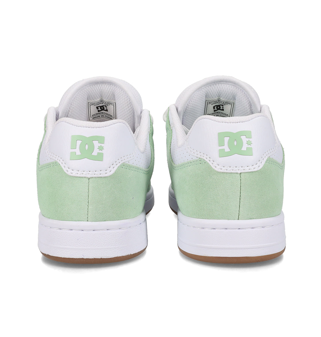 A pair of mint green and white Women’s Manteca 4 Shoes by DC Shoes are shown from the back, featuring the signature DC Shoes logo on each heel counter. The white soles with a brown bottom edge emphasize both the style and performance-driven design.