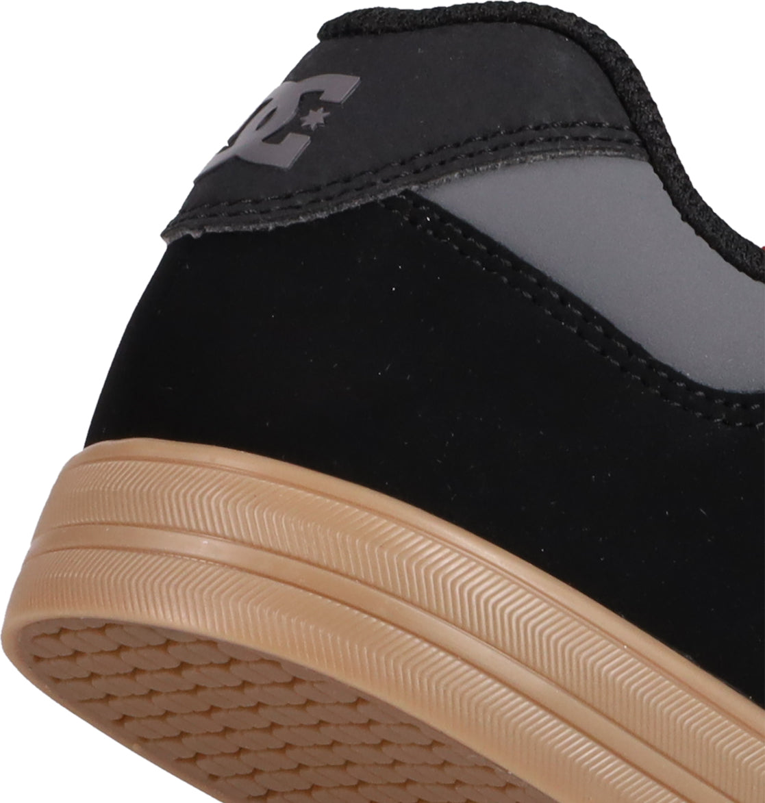 Close-up of the heel of black and gray DC Shoes Kids' Pure Shoes with a tan rubber sole and textured tread. The back features a DC logo with star on the heel tab, blending style and comfort for kids.