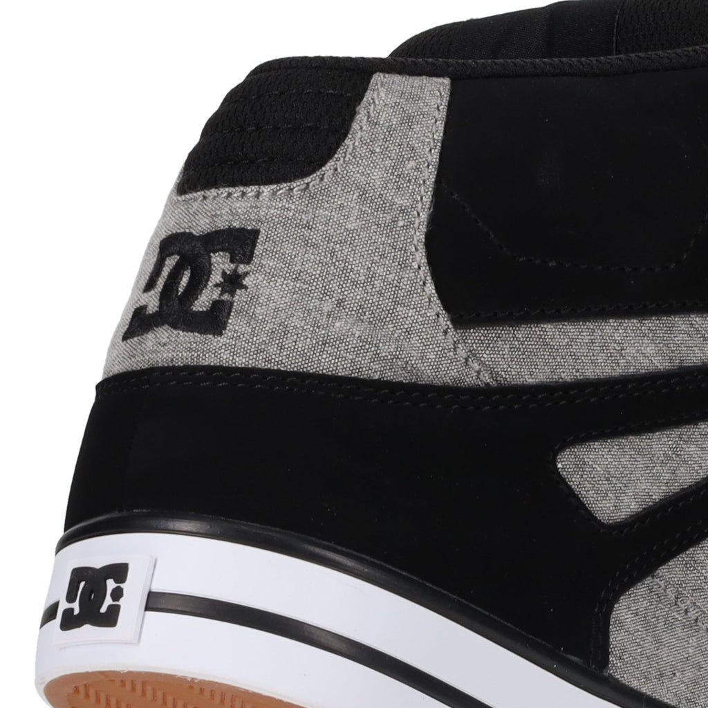 Close-up of the heel of a black and gray DC Shoes Men’s Pure High-Top Shoe, featuring the white DC Shoes logo on both the heel and the side. The outsole is partially visible at the bottom, highlighting these comfortable and durable sneakers.
