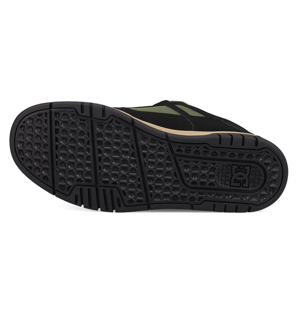 The image shows the black rubber sole of the Men's Stag Shoes by DC Shoes, featuring a textured hexagonal tread and an embossed logo near the heel, emphasizing its durable cupsole designed for skate culture.