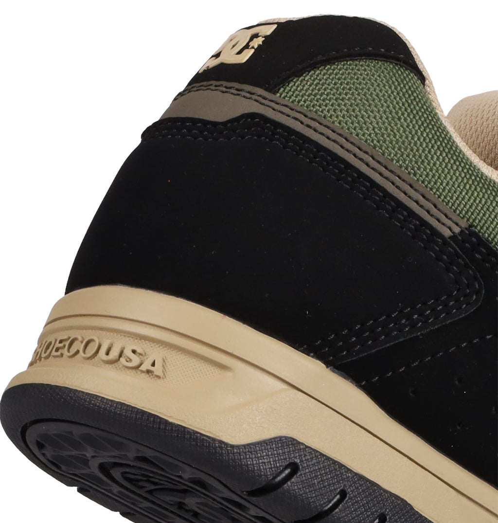 Close-up of the heel on DC Shoes Men's Stag Shoes, showcasing black, olive green, and beige colors with the DC Shoes logo on the back and SHOESUSA embossed on the durable cupsole midsole.