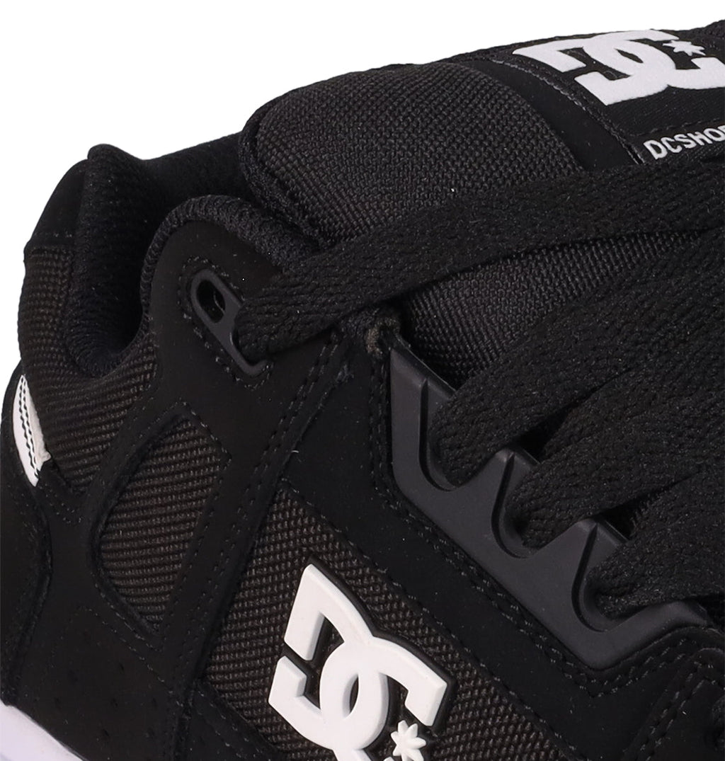 Close-up of the Men's Stag Shoes by DC Shoes in black, featuring visible laces, mesh and leather textures, cupsole construction, and a white DC Shoes logo on the side—ideal for skate culture enthusiasts.