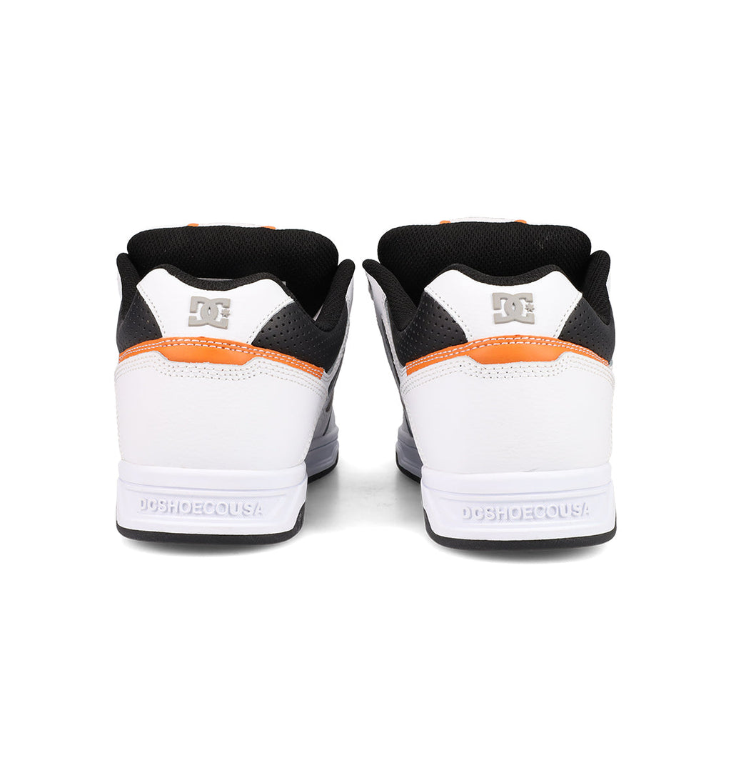 Viewed from the back, DC Shoes Men's Stag sneakers feature white uppers, black collars, orange accents, a DC logo on the heel, and DCSHOECOUSA embossed on the cupsole—ideal for fans of skate culture and the iconic Stag line.