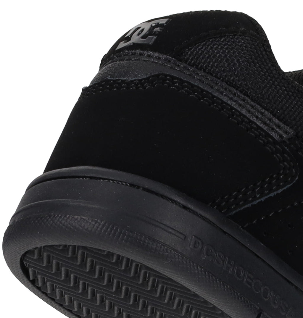 Close-up of the heel and sole of the black Kids’ Stag Shoes by DC Shoes, showcasing the brand’s logo on the heel, durable cupsole construction, and textured rubber tread on the outsole.