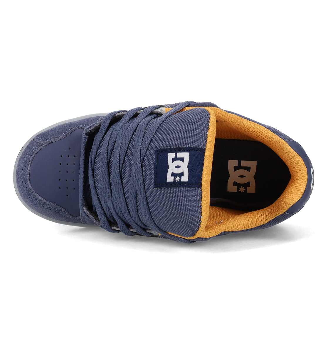 Top view of the Kids’ Stag Shoes by DC Shoes in navy blue, featuring a mustard yellow inner lining and a white DC logo on the padded tongue. This minimal silhouette offers wide, flat laces, visible stitching details, and the clean style of a classic vulc shoe—making it an essential everyday option for your collection.