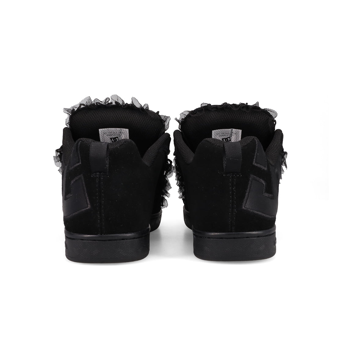 Back view of DC Shoes Women's Court Graffik SD shoes, featuring a black suede upper, frayed ankle details, black soles, and a textured black "E" design on the heel, placed side by side on a white background.