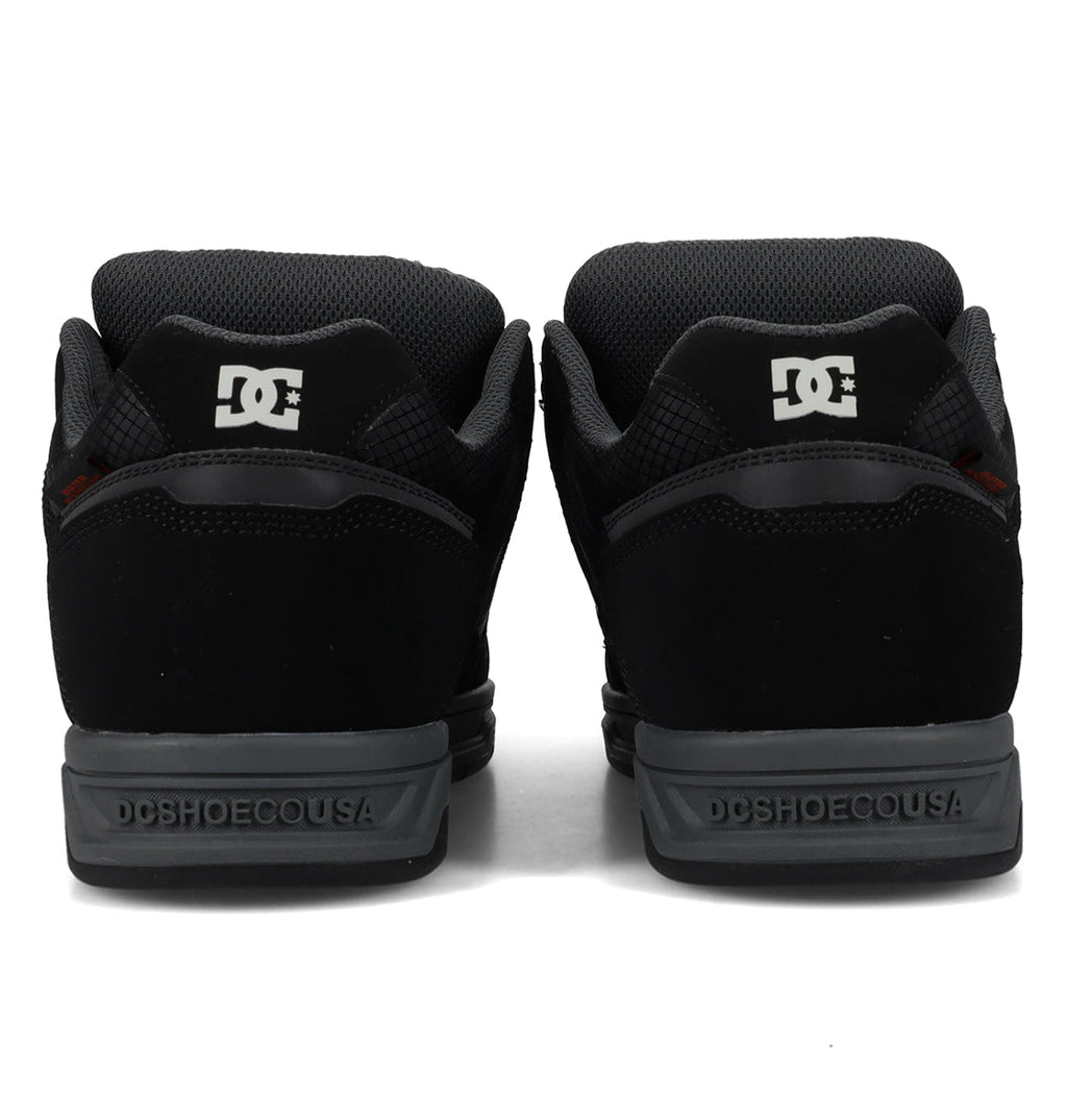 Back view of a pair of Men’s Stag Winterized Shoes by DC Shoes in black, showcasing gray soles with the iconic DC logo on the heel and “DCSHOECOUSA” text along the midsole. Crafted with lightweight cushioning to deliver enhanced comfort during every session.