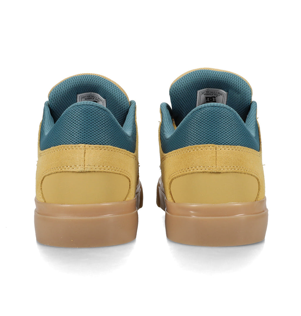 A pair of DC Shoes Men’s Onyx Skate Shoes in yellow with teal lining and brown soles, shown from the back against a white background, features a minimal silhouette reminiscent of the classic vulc shoe style.