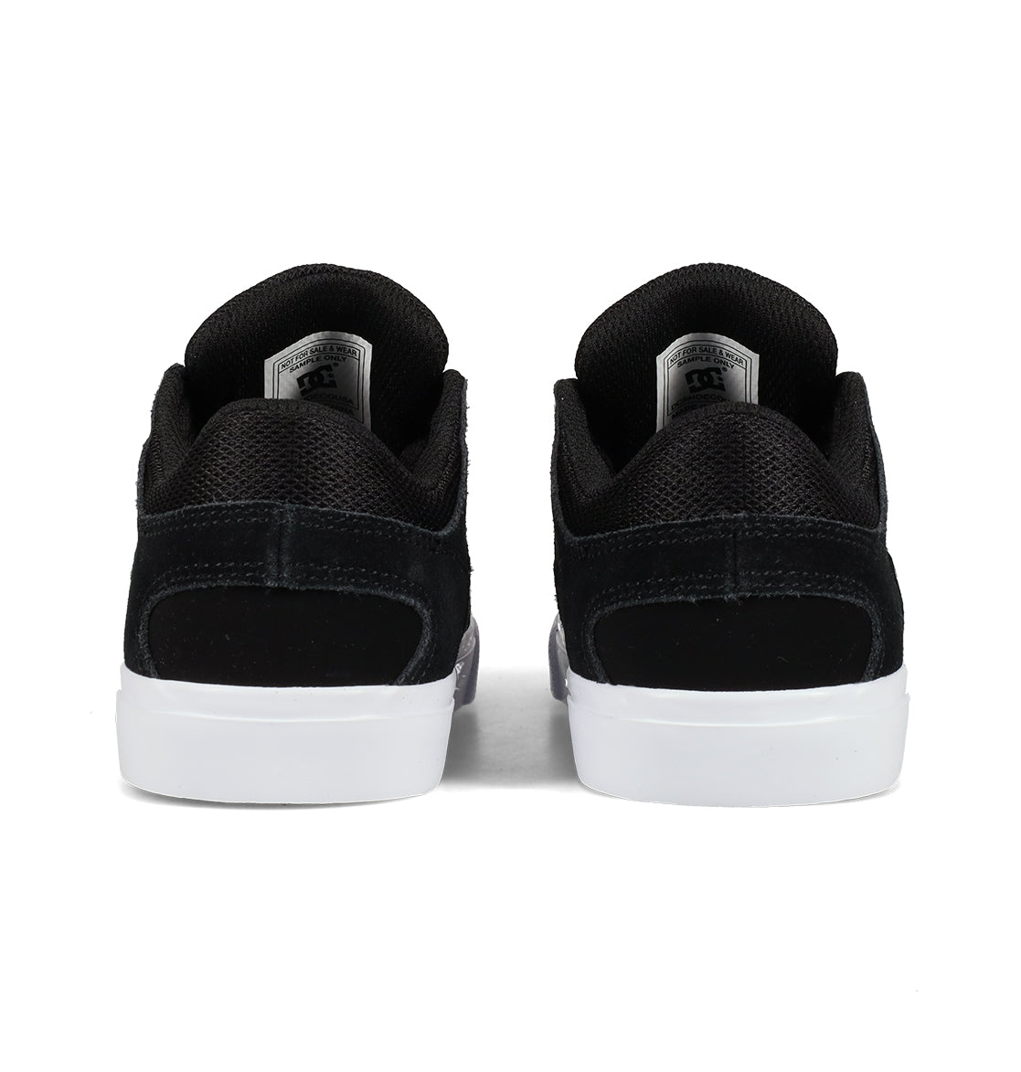 A pair of DC Shoes Kids’ Onyx Shoes in black with white soles is shown from the back, highlighting the heel and interior labels—these sneakers boast a minimal silhouette, making them perfect for everyday wear.