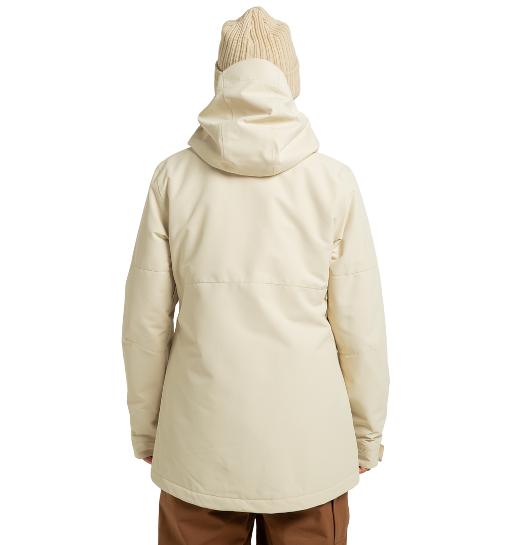 A person is shown from behind, standing against a plain white background, wearing a cream-colored DC Shoes Women’s Cruiser Insulated Jacket made from recycled polyester. The jacket features advanced weather defense technology for added protection and is paired with a tan knit beanie and brown pants.