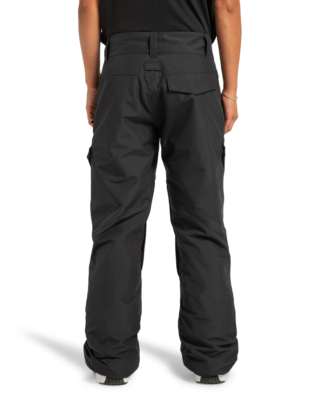 A person is seen from the back wearing loose-fitting black DC Shoes Women’s Nonchalant Insulated Snow Pants, which feature multiple pockets and are designed for outdoor or winter activities. These women’s snow pants are made with recycled polyester fabric and PROFILL insulation. The person is also wearing a black shirt.