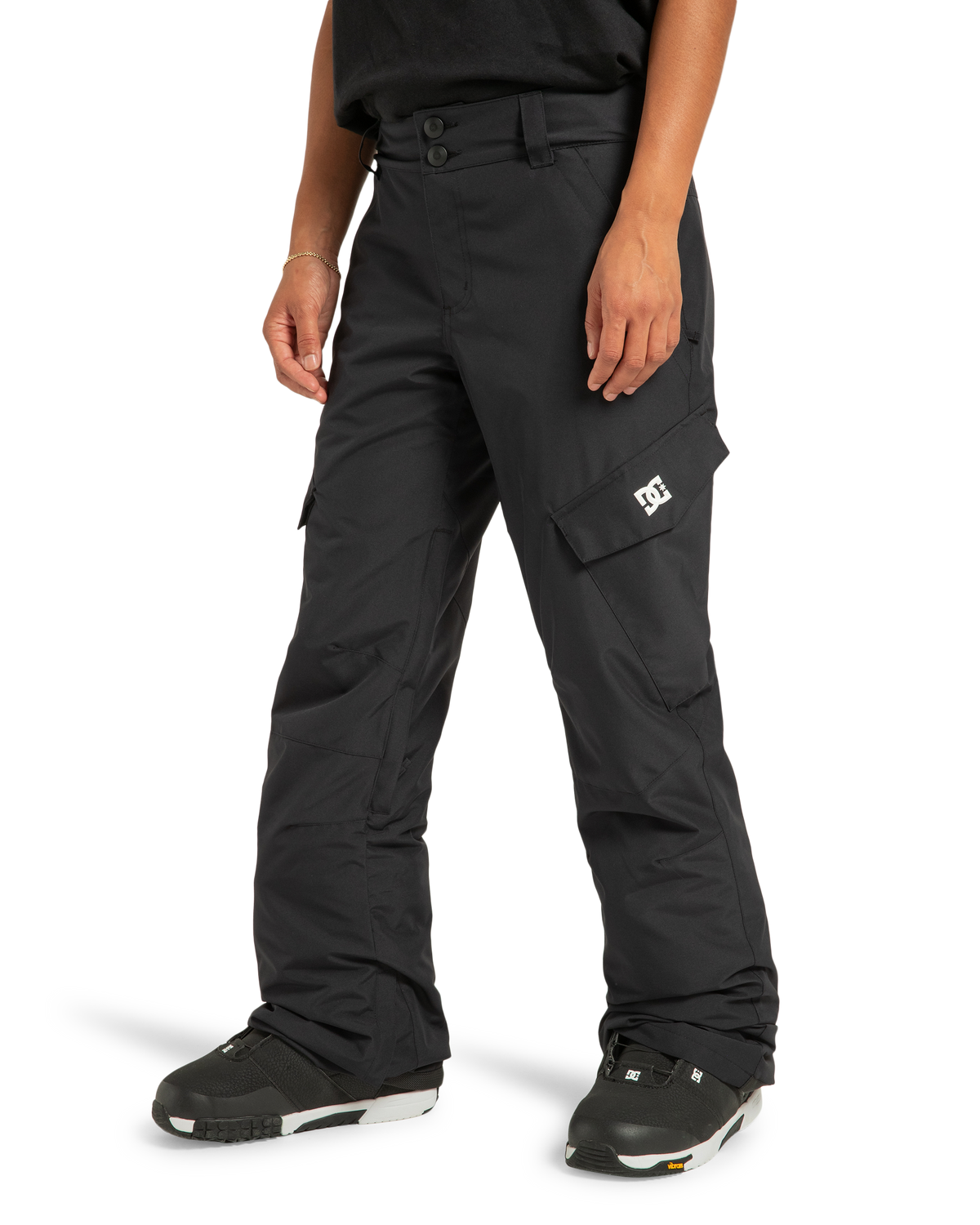 A person wearing DC Shoes Women’s Nonchalant Insulated Snow Pants—crafted from recycled polyester material and featuring PROFILL insulation—with black snow boots and a black shirt, stands against a white background.