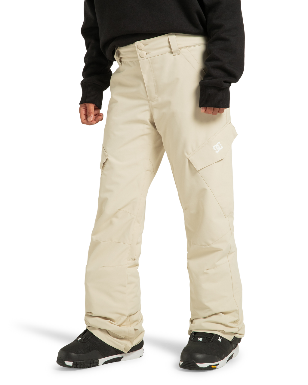 A person wearing DC Shoes Women’s Nonchalant Insulated Snow Pants in light beige—crafted from recycled polyester—paired with a black sweatshirt and black snow boots, stands against a white background.