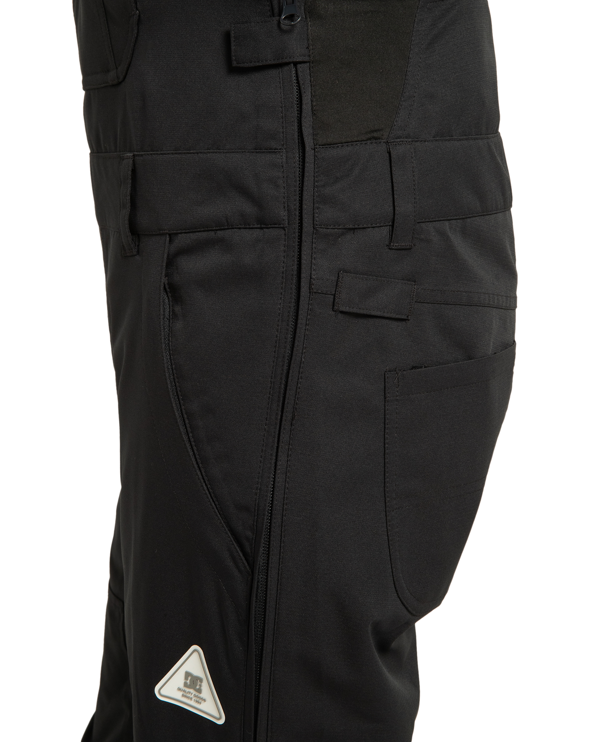 Close-up of the DC Shoes Women’s Crusade Shell Bib in black, featuring a side zipper, pockets, belt loops, and a small triangular reflective patch near the knee—making it an ideal choice for women’s adventure gear that delivers waterproof protection in any environment.
