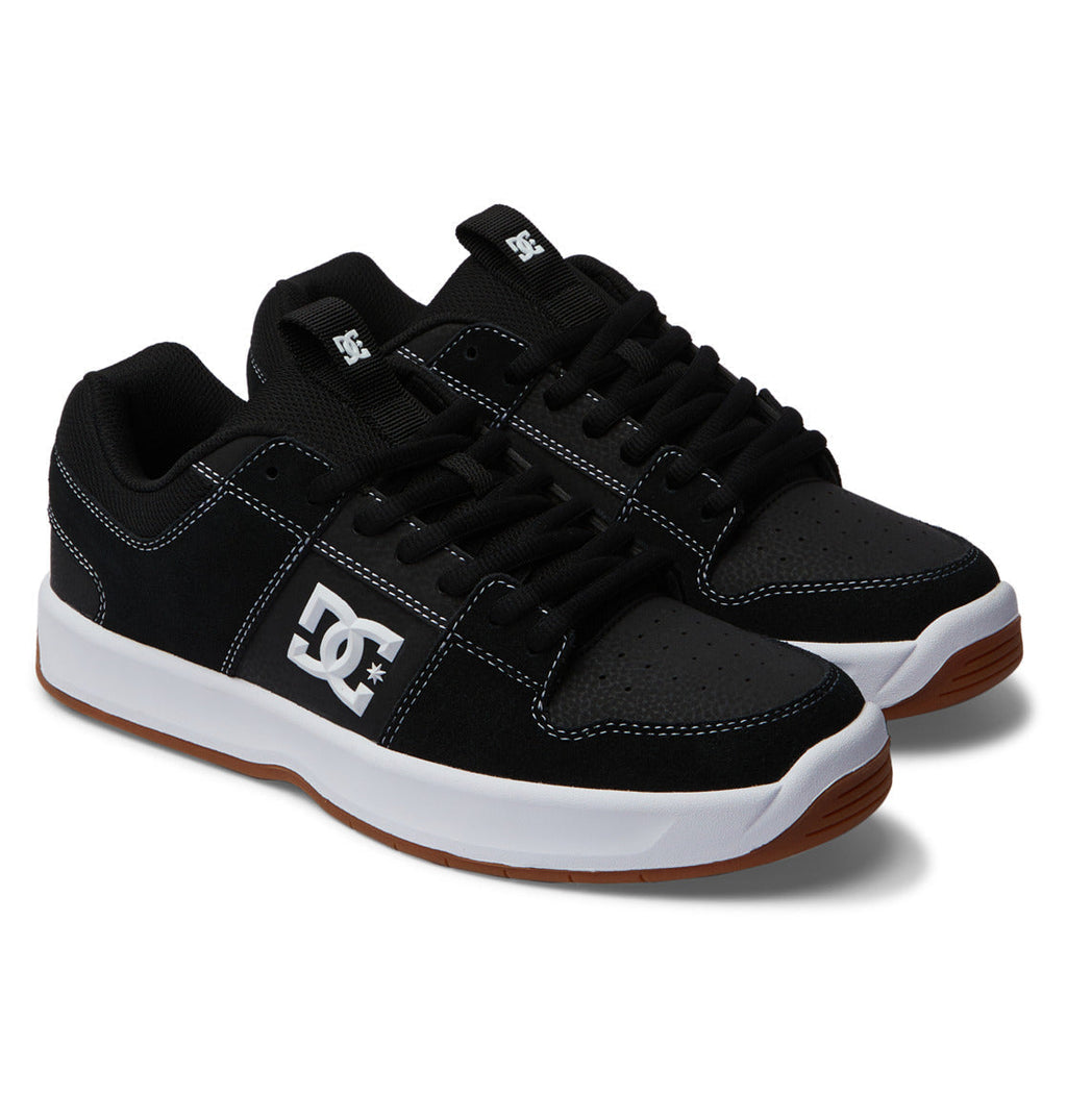 A pair of Men’s Lynx Zero Shoes by DC Shoes in classic black, featuring white stitching, white midsoles, brown gum outsoles, and the signature DC logo on the side—ideal for fans of timeless skate footwear.