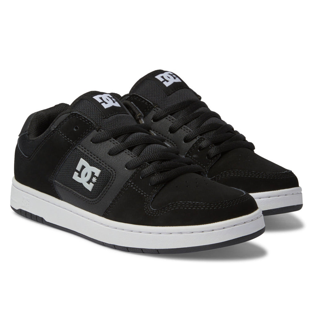 Showcasing the Men’s Manteca 4 Shoes from DC Shoes, this pair features a sleek black design with white soles, black laces, and bold white DC branding on both the side and tongue. The skate shoes are presented at an angle to highlight their performance-focused construction from both side and top perspectives.