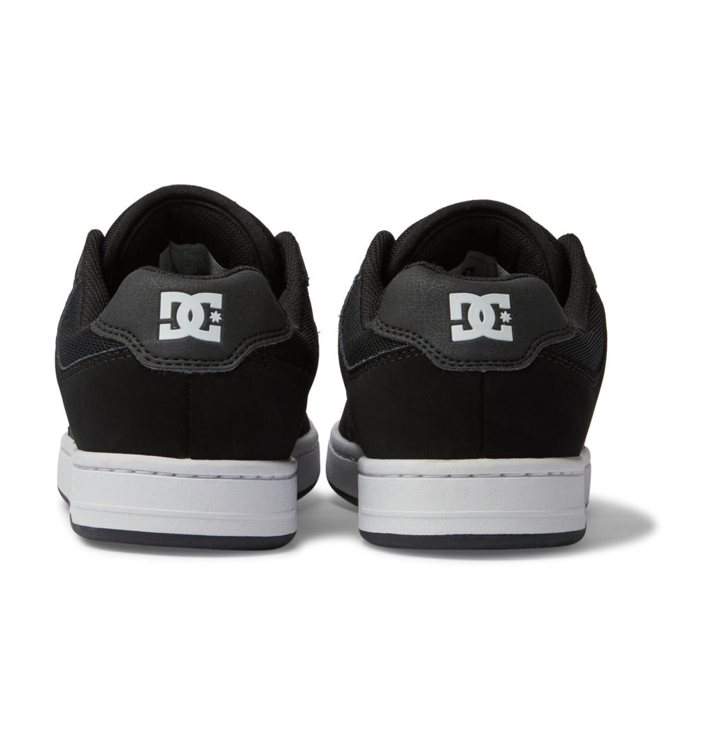 A pair of DC Shoes Men’s Manteca 4 Shoes in black, shown from the back, featuring a performance-driven design with white DC logos on the heels and clean white midsoles.