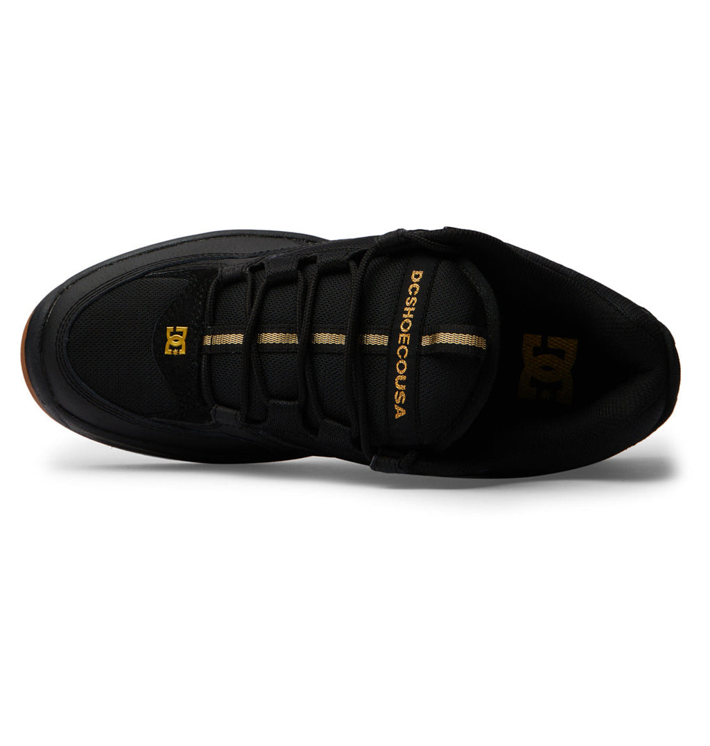 Top-down view of a DC Shoes Men’s Kalynx Zero black low-top sneaker featuring gold DCSHOECOUSA branding on the tongue, a gold DC logo on the side, black laces, and a gum sole visible at the edges.