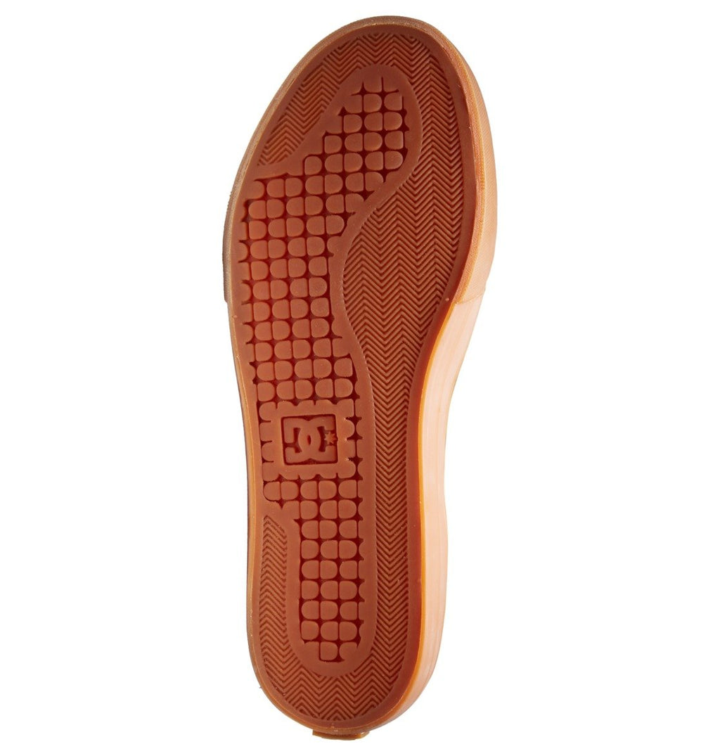 The image displays the sole of a brown DC Shoes Men’s Pure High-Top Shoe, featuring a textured grip pattern and a small embossed DC Shoes logo at the center, showcasing the durability and comfort characteristic of this best-selling style.