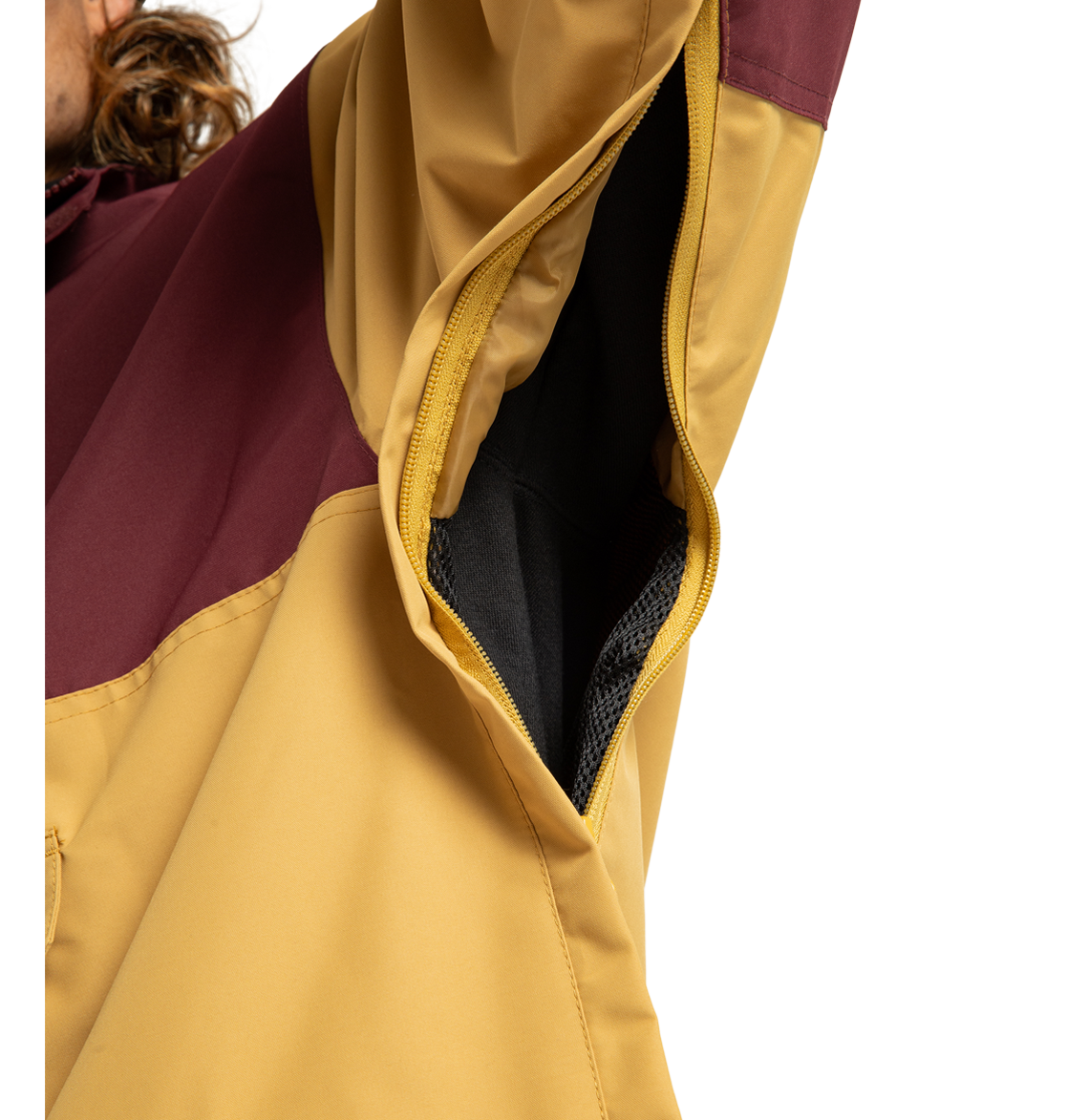 Close-up of the Men’s DC-43 Anorak Shell Jacket by DC Shoes, focusing on its zippered armpit vent that reveals the interior mesh lining. The jacket features a yellow color with a maroon upper sleeve section, and the zipper is partially open.