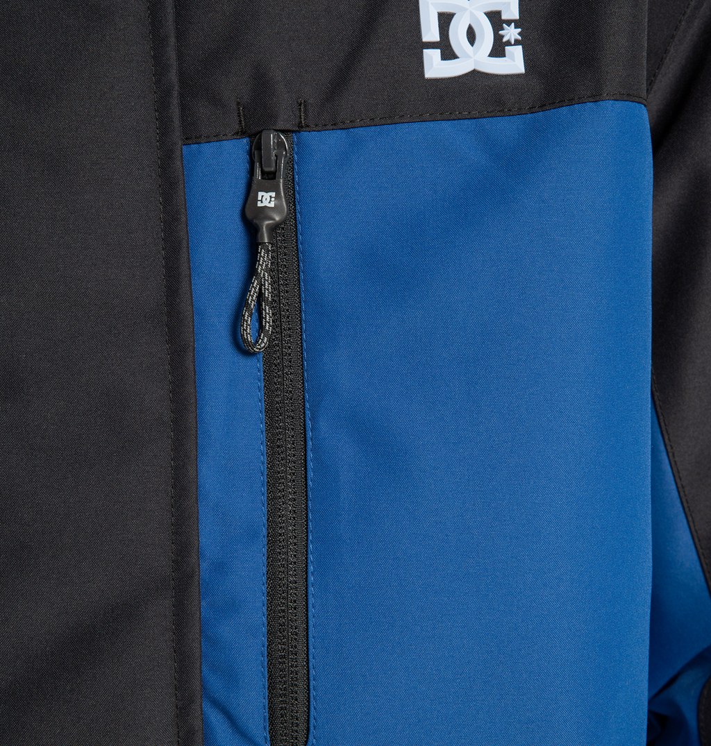 Close-up of the DC Shoes Men’s Defiant Insulated Jacket in black and blue, crafted from recycled polyester fabric and featuring Weather Defense 10 technology, with a vertical zippered pocket and a small DC Shoes logo near the top.