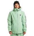 A person wearing the DC Shoes Unisex Basis Insulated Jacket in mint green, paired with matching pants and a black beanie, stands facing forward. This winter jacket, ideal for cold-weather activities, features a logo on the chest and text on the left sleeve. Made from recycled polyester, it offers both style and sustainability.