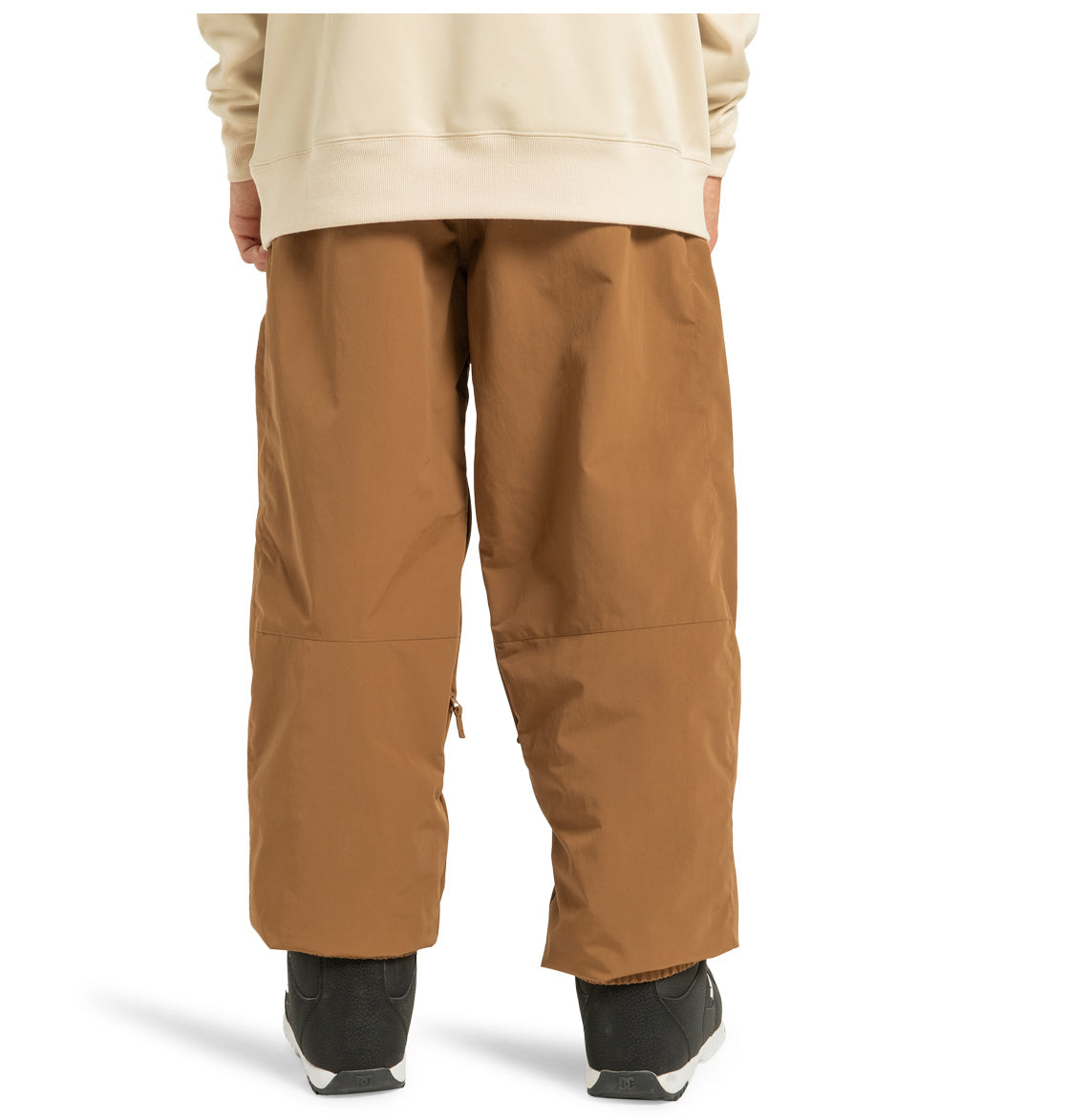 A person is shown from the back, standing on a white background, wearing loose brown Unisex Primo Shell Pants by DC Shoes and black sneakers—an excellent option for outdoor enthusiasts who need dependable weather protection.