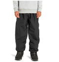 A person is wearing DC Shoes Unisex Primo Snow Pants in black, made from recycled polyester, along with a gray sweatshirt and black athletic shoes, standing against a plain white background.