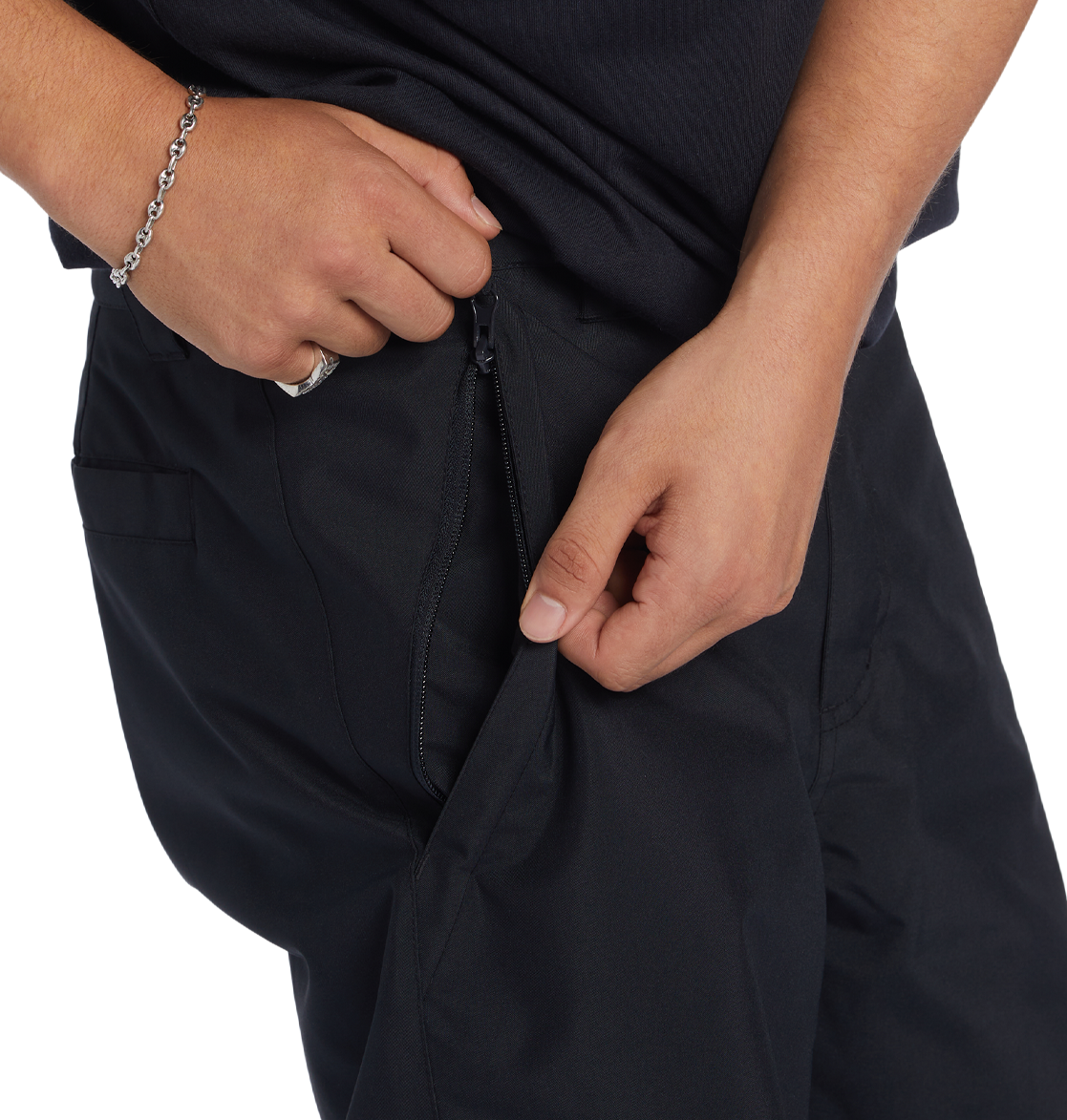 A person, showing only their lower torso and hands, is unzipping a side pocket while wearing DC Shoes Men’s Insulated Chino Pants and a black shirt.
