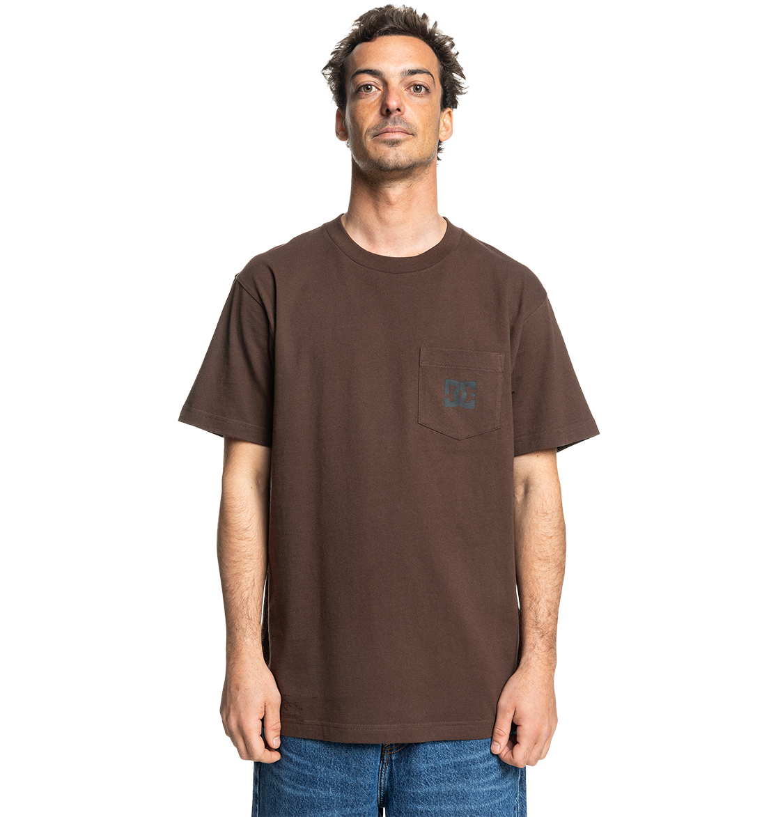 A man faces forward against a white background wearing the Men's DC Star Pocket Tee by DC Shoes—a relaxed fit brown cotton skate shirt with a chest pocket—paired with blue jeans.