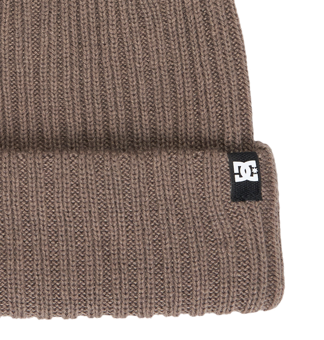 A close-up of the DC Shoes Fish N Destroy 2 beanie highlights its brown ribbed knit design and folded brim, crafted from recycled fibers for an eco-friendly appeal. This comfortable beanie features a small black and white DC Shoes logo tag on the brim.