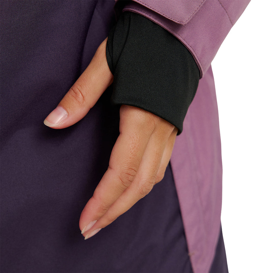 A close-up of a person’s hand with neatly manicured nails, partially covered by the black sleeve of the DC Shoes Everfrost Jacket, resting against a purple and mauve garment.