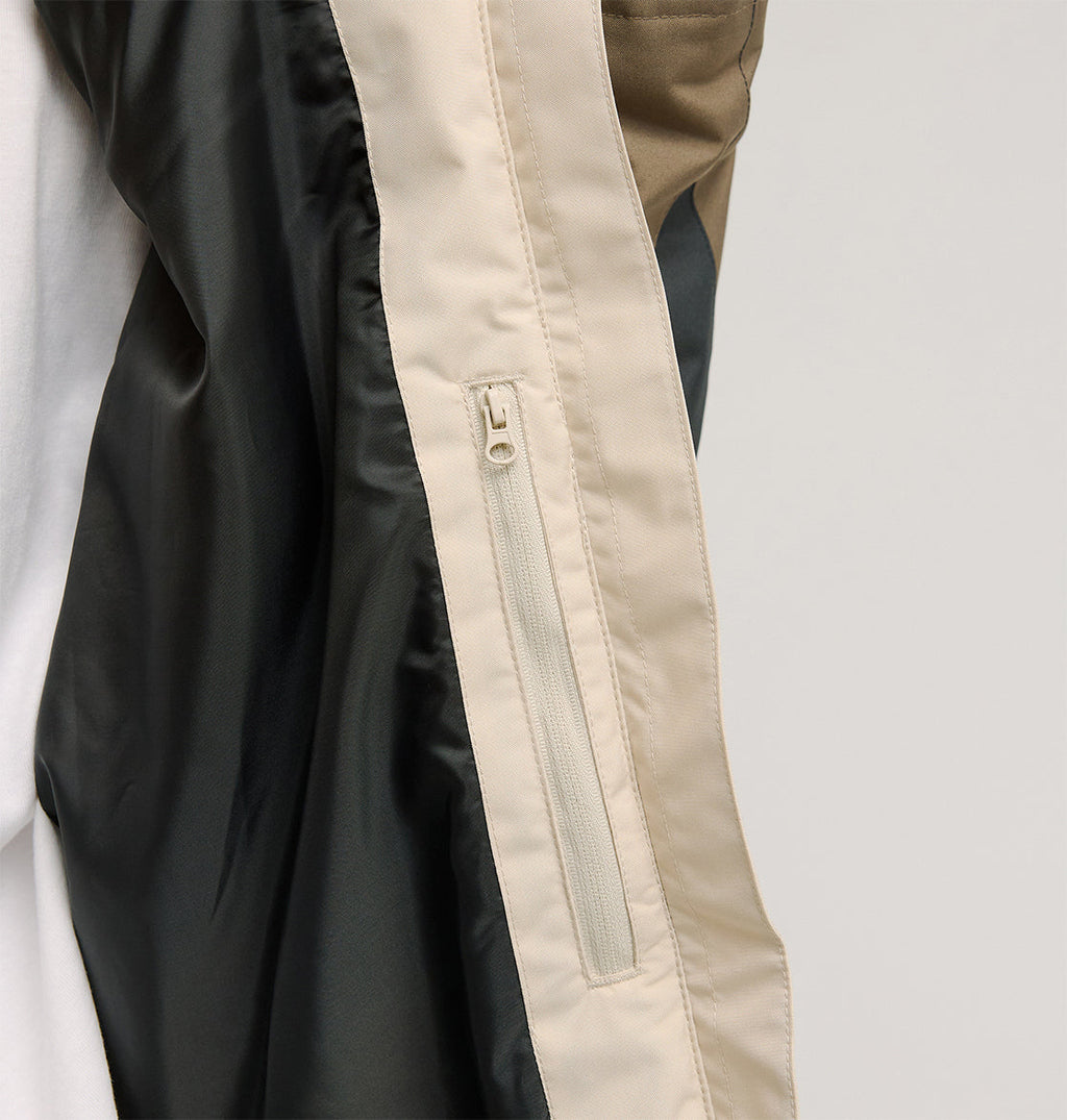 Close-up of the DC Shoes Everfrost Jacket sleeve in beige and black, featuring a vertical zipper pocket detail, shown against a plain background.